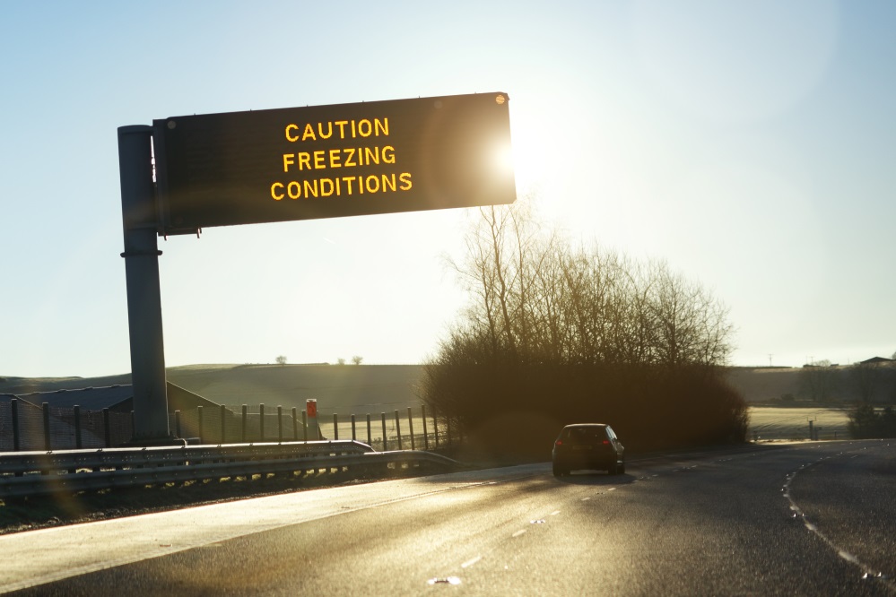 Sign above motorway reading 'Caution, freezing conditions'.